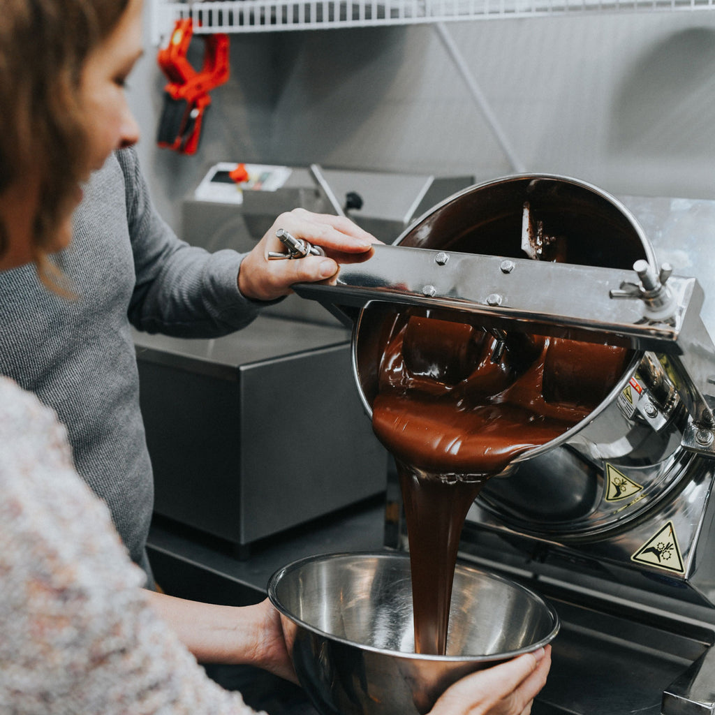 Uncharted Chocolate founder, Nicole Guy, pouring liquid chocolate into a stainless steel bowl.